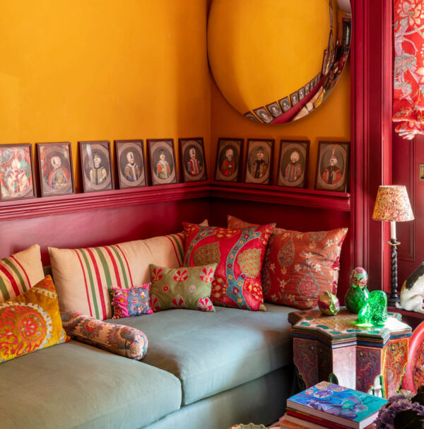 Mark Luscombe-Whyte, Rifat Ozbek, indoors, interior, nobody, traditional, living room, salon, detail, colour, yellow, golden yellow, wall, cornice, dado, painted, seating, upholstered, banquette, soft furnishing, cushion, rug, pattern, patterned, striped, floral, chinoiserie, fabric, textile, kente, objects, antiques, mirror, round mirror, convex mirror, artwork, painting, portrait painting, display, collection, vibrant colour, colourful, comfortable, vintage, inspiration, creativity, individuality, eclectic, flamboyant, theatrical, romantic, bohemian,